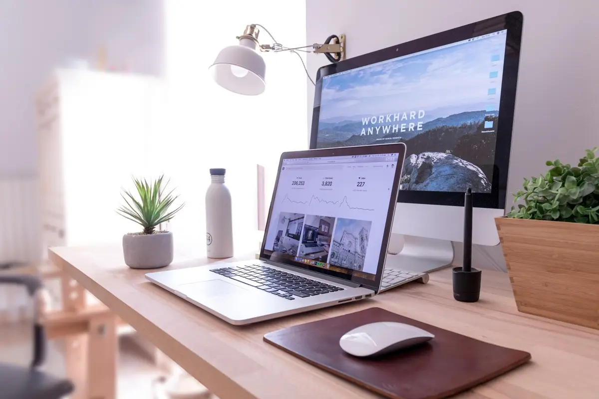 A laptop and a desktop computer on a wooden desk